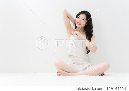 美麗的年輕女子盤腿坐著,擔心她的腋窩除毛 美麗的年輕女子盤腿坐著,擔心她的腋窩除毛 119163334