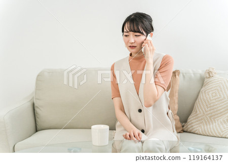 Asian woman feeling sad, shocked and stressed while having a conversation using her smartphone at home Asian woman feeling sad, shocked and stressed while having a conversation using her smartphone at home 119164137