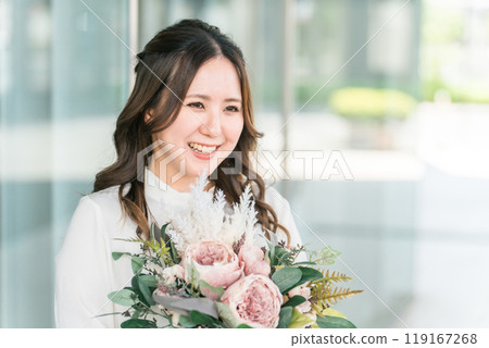 A young business woman receives a bouquet of flowers from a colleague at a farewell party, welcome party, and childcare leave. A young business woman receives a bouquet of flowers from a colleague at a farewell party, welcome party, and childcare leave. 119167268
