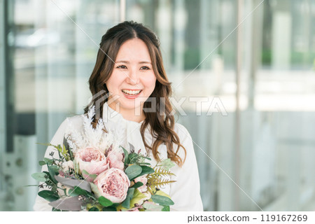 一位年輕的女商人在歡送會、歡迎會和育嬰假期間收到同事送的一束鮮花。 119167269
