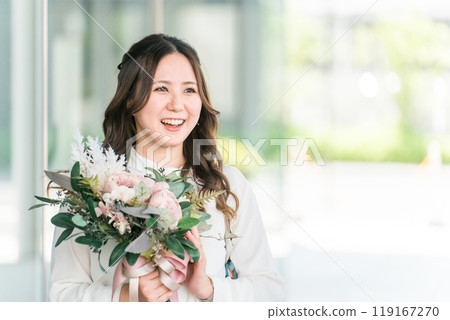 A young business woman receives a bouquet of flowers from a colleague at a farewell party, welcome party, and childcare leave. 119167270