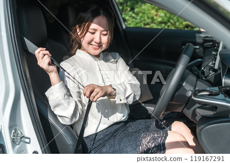 Female driver getting into a car and wearing a seatbelt (traffic rules, safe driving, traffic safety) 119167291