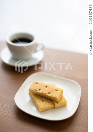 Cookies and coffee on a table by a window with sunlight filtering through the trees Cookies and coffee on a table by a window with sunlight filtering through the trees 119167486