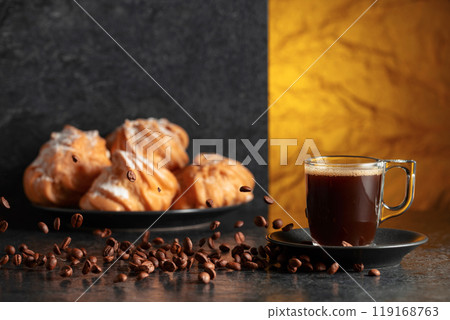 Black coffee in glass cup and coffee beans in motion on a black table. Black coffee in glass cup and coffee beans in motion on a black table. 119168763