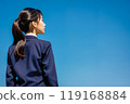 藍天背景下，一個穿著校服的女孩的後視圖。 119168884