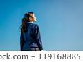 藍天背景下，一個穿著校服的女孩的後視圖。 119168885
