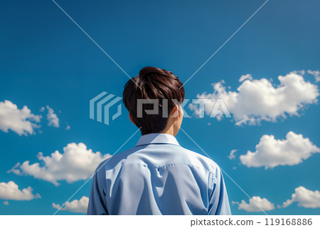 藍天背景下,一個穿著校服的男孩的後視圖。 藍天背景下,一個穿著校服的男孩的後視圖。 119168886