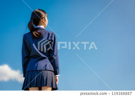 藍天背景下,一個穿著校服的女孩的後視圖。 藍天背景下,一個穿著校服的女孩的後視圖。 119168887