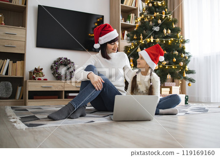 Mother and daughter share holiday moments by the Christmas tree Mother and daughter share holiday moments by the Christmas tree 119169160