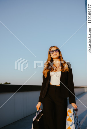 Stylish woman with shopping bags under blue sky 119169277