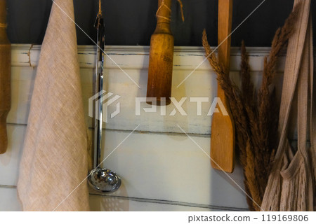 Cozy kitchen utensils hanging on rustic wooden wall in a warm home setting inviting culinary creativity 119169806