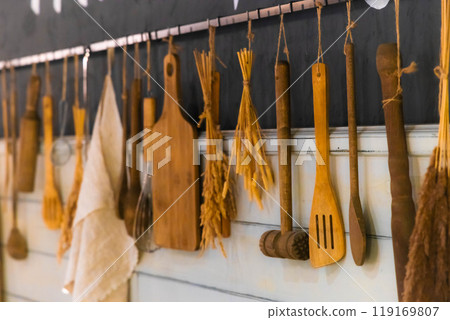 Rustic kitchen utensils arranged creatively on a wooden wall in a cozy cooking space filled with warmth 119169807