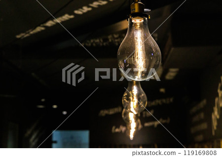 Elegant vintage light bulbs hanging in a cozy cafe with dark walls and handwritten decor in the evening Elegant vintage light bulbs hanging in a cozy cafe with dark walls and handwritten decor in the evening 119169808