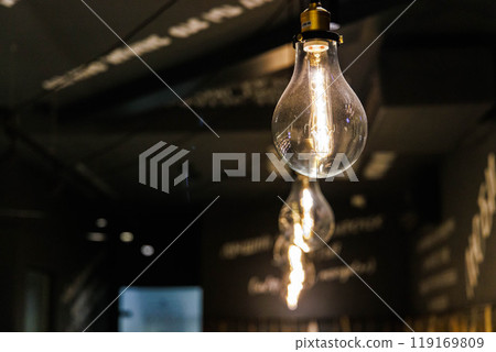 Elegant hanging light bulbs illuminate a modern cafe interior in a cozy atmosphere during the evening hours Elegant hanging light bulbs illuminate a modern cafe interior in a cozy atmosphere during the evening hours 119169809
