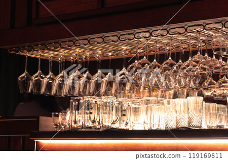 Elegant display of crystal glasses and tumblers gleaming under warm bar lighting in a cozy setting Elegant display of crystal glasses and tumblers gleaming under warm bar lighting in a cozy setting 119169811