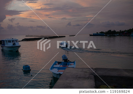 Serene evening boat ride in the Maldives, as the sun sets over tranquil waters and coral reefs Serene evening boat ride in the Maldives, as the sun sets over tranquil waters and coral reefs 119169824