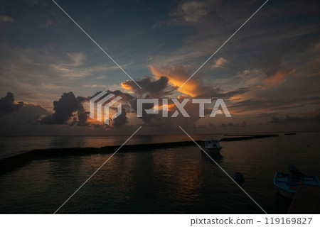 Stunning sunset over tranquil waters in Maldives with boats silhouetted against colorful clouds Stunning sunset over tranquil waters in Maldives with boats silhouetted against colorful clouds 119169827