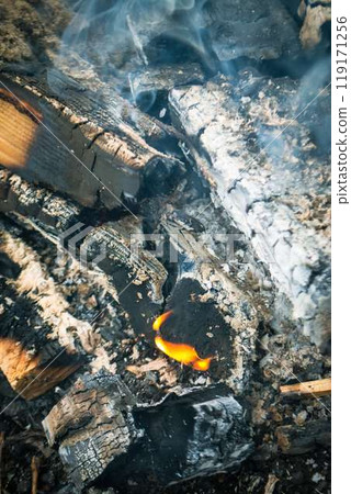 A fire burns in a campfire with a red fire in the background. A fire burns in a campfire with a red fire in the background. 119171256