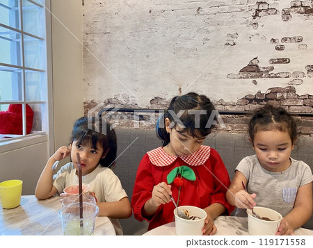 Group of kids eating chocolate ice cream at a table in a cafe 119171558