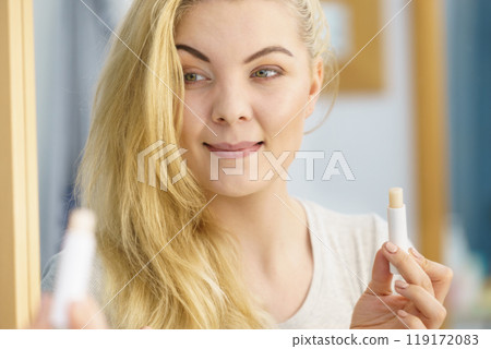 Woman using lip balm on her lips 119172083