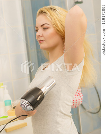 Woman drying sweat stains using hair dryer Woman drying sweat stains using hair dryer 119172092