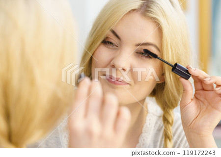 Woman using mascara on her eyelashes Woman using mascara on her eyelashes 119172243