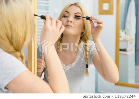 Woman using mascara on her eyelashes Woman using mascara on her eyelashes 119172244