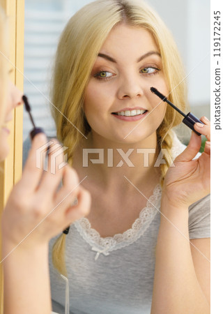 Woman using mascara on her eyelashes Woman using mascara on her eyelashes 119172245