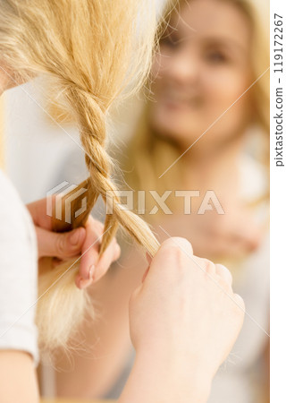 Woman making braid on blonde hair 119172267