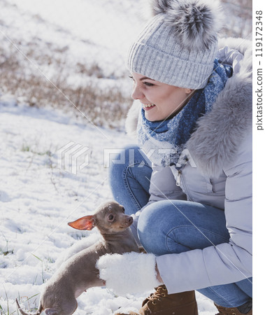Woman playing with dog during winter 119172348