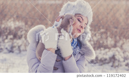 Woman playing with dog during winter 119172402
