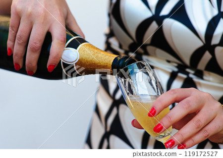 Woman Pouring Champagne into Glass at Celebration Event 119172527