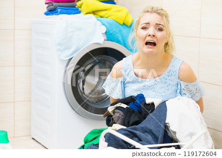 Unhappy woman having a lot of laundry Unhappy woman having a lot of laundry 119172604