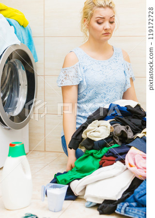 Unhappy girl sorting dirty clothes laundry. Unhappy girl sorting dirty clothes laundry. 119172728