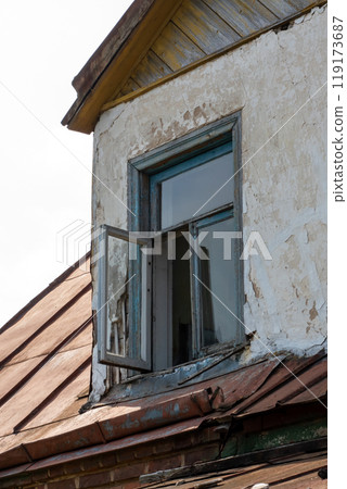 An aged building characterized by a rusty roof and shattered windows 119173687