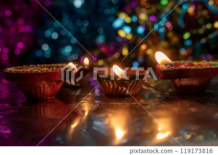 Diwali celebration background with glowing clay lamps and colorful lights 119173816