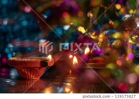 Diwali celebration background with glowing clay oil lamps and colorful lights bokeh 119173827