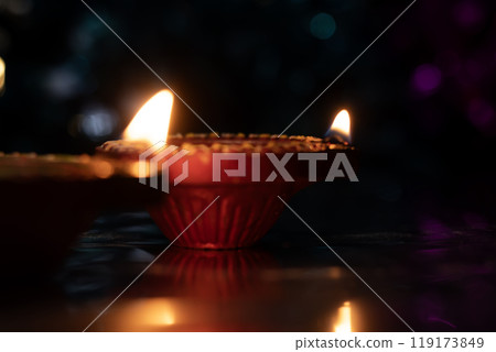 Traditional Diwali Diyas and beautiful light reflection with bokeh effect on dark background for Diwali festival celebration. Closeup 119173849