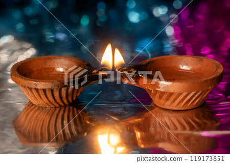 Diwali celebration lit clay lamp and light reflected on colorful background. 119173851