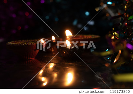 Beautiful scene with light reflection of illuminated diyas on traditional Diwali festival celebration with colorful bokeh effects background Beautiful scene with light reflection of illuminated diyas on traditional Diwali festival celebration with colorful bokeh effects background 119173860
