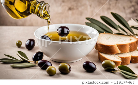 Olive oil is poured from a bottle into a bowl. There are slices of bread nearby. Olive oil is poured from a bottle into a bowl. There are slices of bread nearby. 119174465