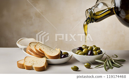 Olive oil is poured from a bottle into a bowl. There are slices of bread nearby. 119174468