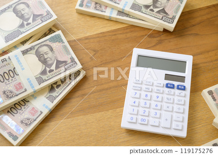 A stack of bills and a calculator on a desk (new bill version) 119175276