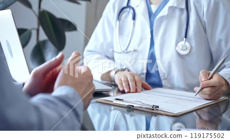 Doctor woman is writing something while consulting man patient on the glass desk and a clipboard in medical office. Medicine concept Doctor woman is writing something while consulting man patient on the glass desk and a clipboard in medical office. Medicine concept 119175502