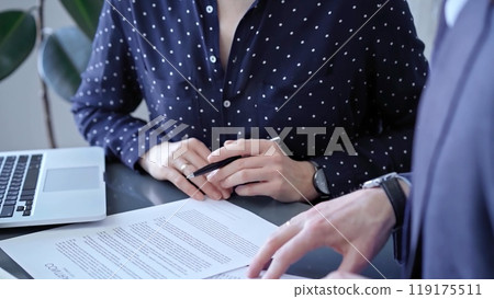 Detailed view of two business people or lawyers signing a contract with a laptop nearby Detailed view of two business people or lawyers signing a contract with a laptop nearby 119175511