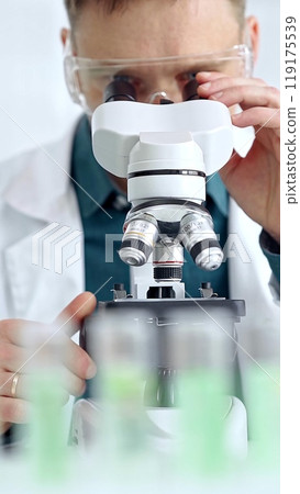 Man scientist with protective glasses using microscope in laboratory. Microbiology science concept 119175539