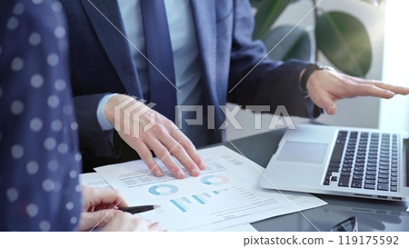 Two professionals analyzing a pie chart during a strategic business meeting. Business meeting with graph analysis Two professionals analyzing a pie chart during a strategic business meeting. Business meeting with graph analysis 119175592