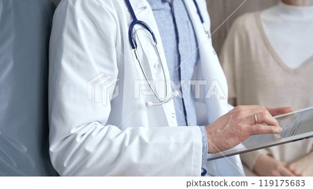 Doctor and patient. Close-up of a doctor's hand taking notes on a clipboard with a woman in the background. Medicine and Health care Doctor and patient. Close-up of a doctor's hand taking notes on a clipboard with a woman in the background. Medicine and Health care 119175683