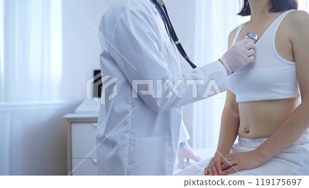 Doctor and patient. Physician wearing white medical gloves is using stethoscope examining woman lungs in clinic. Medicine concept 119175697