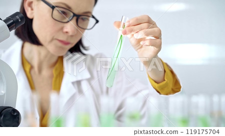 Scientist examining lab tube with a green fluid. Microbiology and science concept 119175704